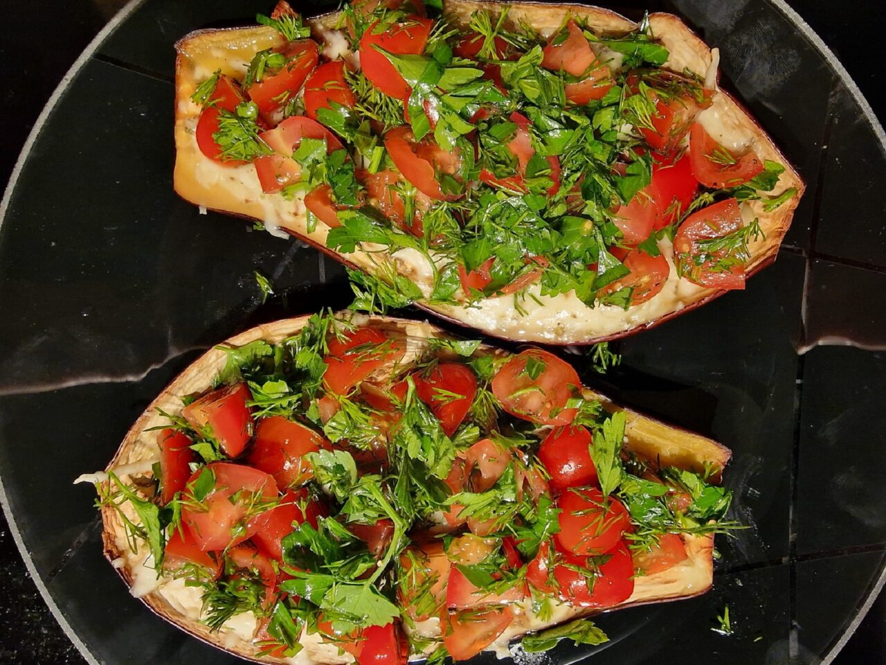 Oven-baked eggplant halves topped with melted cheese and tomato-herb mixture