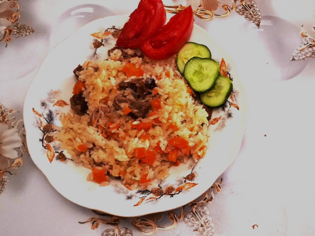 Close-up of rice pilaf with tender beef ribs and vegetables