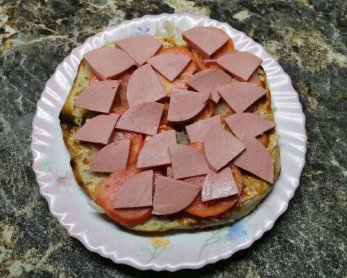 Нарезанную кусочками вареную колбасу