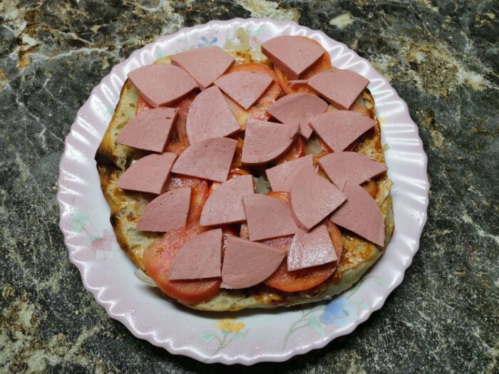 Нарезанную кусочками вареную колбасу