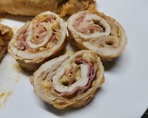 Sliced chicken roll showing cheese and onion filling inside bacon crust