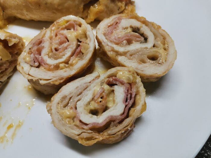 Sliced chicken roll showing cheese and onion filling inside bacon crust