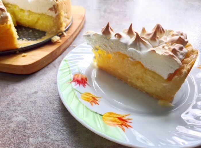 Slice of lemon meringue cake with fluffy meringue cloud