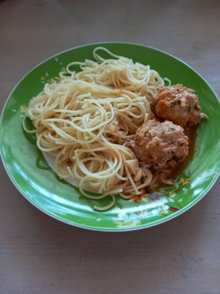 Plate of spaghetti with homemade meatballs and grated Parmesan