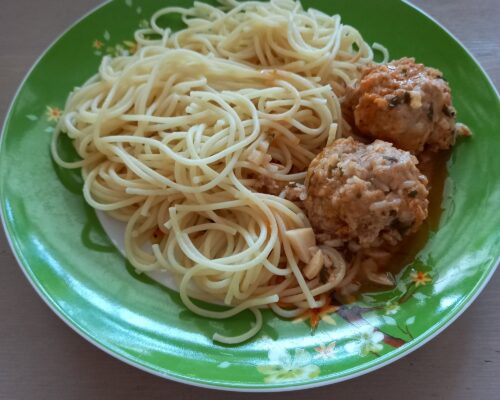 Plate of spaghetti with homemade meatballs and grated Parmesan