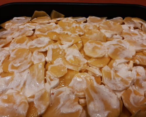 Spread mayonnaise on the top layer of potatoes.