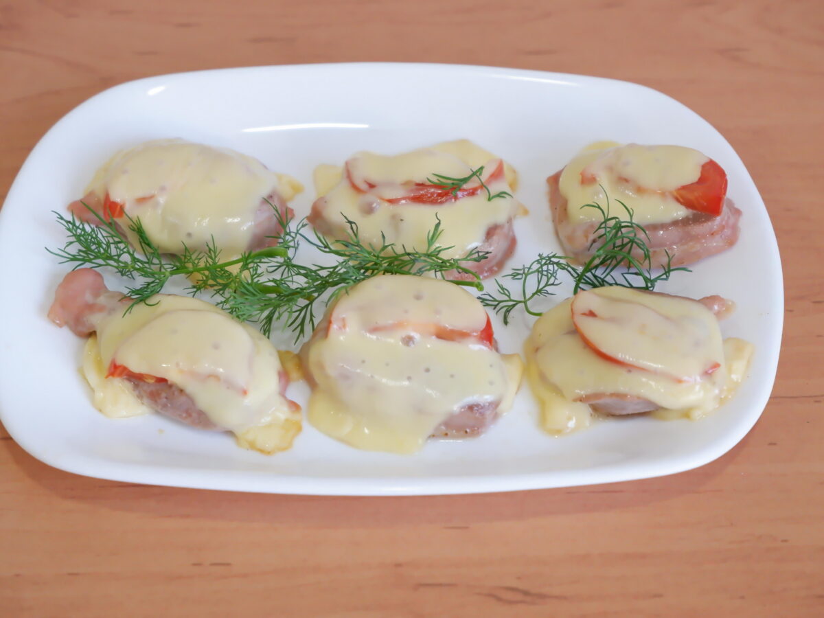 Baked pork medallions topped with tomato and melted cheese