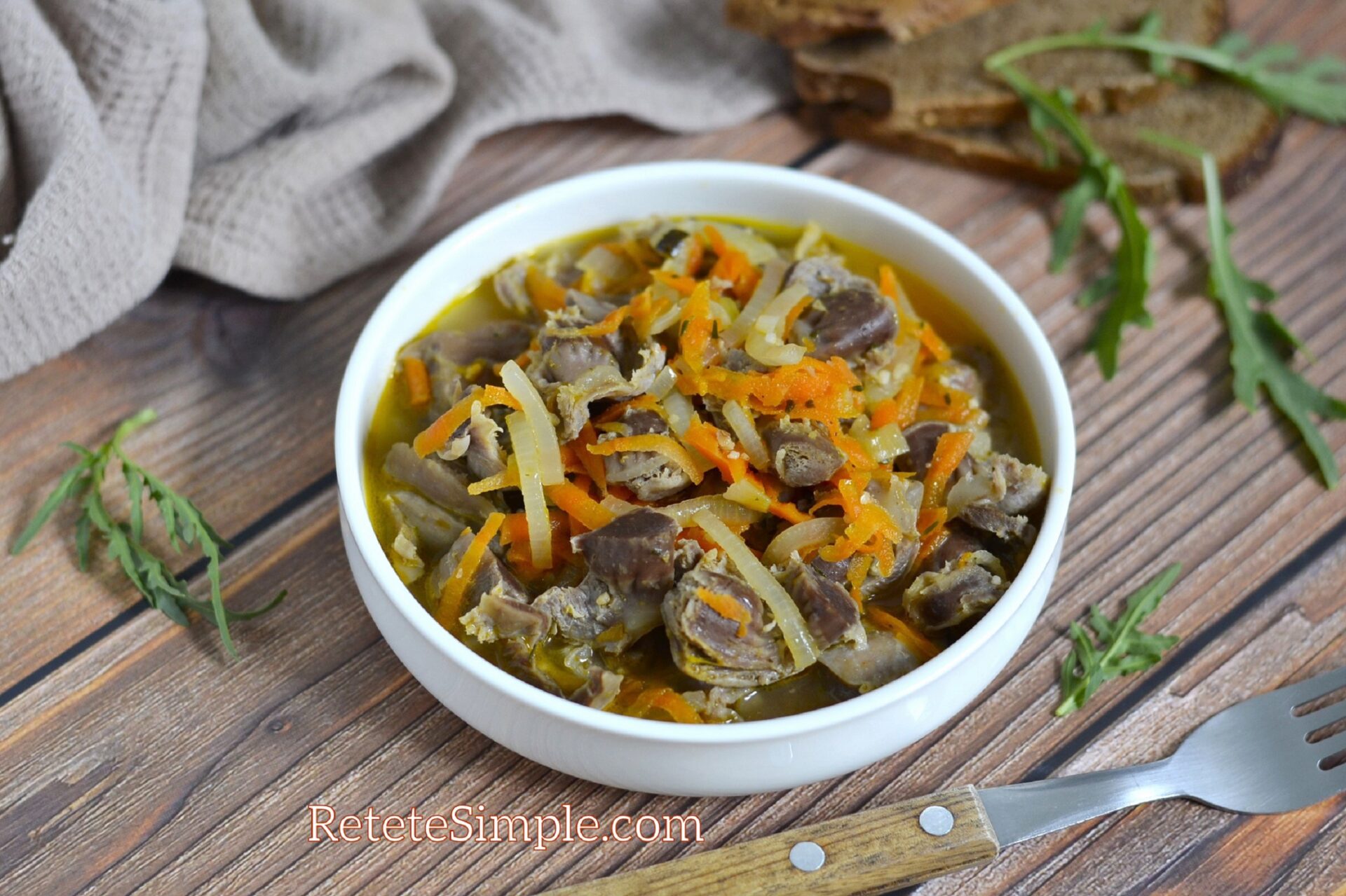 Bowl of hearty chicken gizzards goulash with carrots and onions