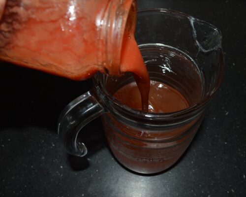 Pour tomato juice into a jug of water