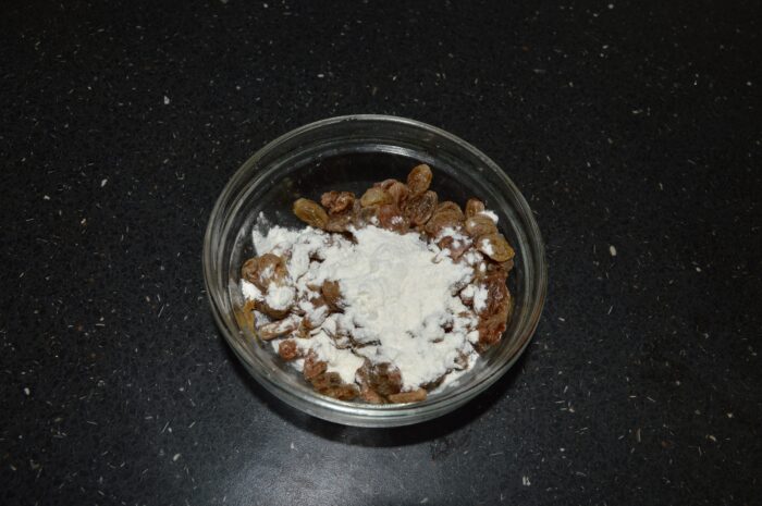 Sprinkle a little flour over the drained raisins