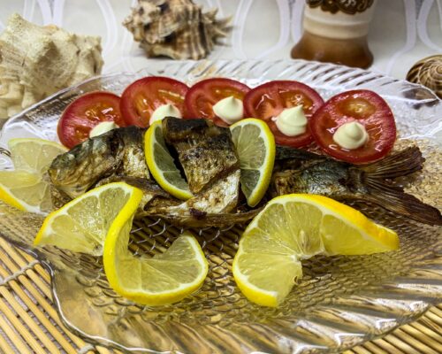 Serve the cooked carp garnished with lemon slices and vegetables