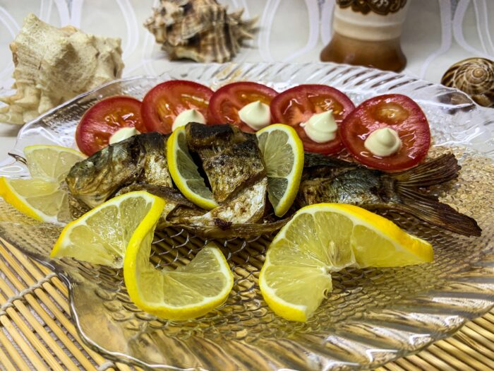 Serve the cooked carp garnished with lemon slices and vegetables