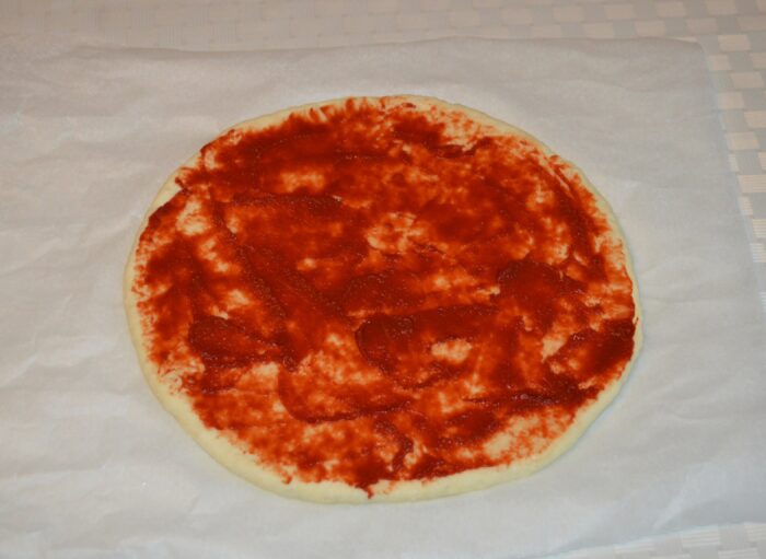 Spread tomato paste over the dough