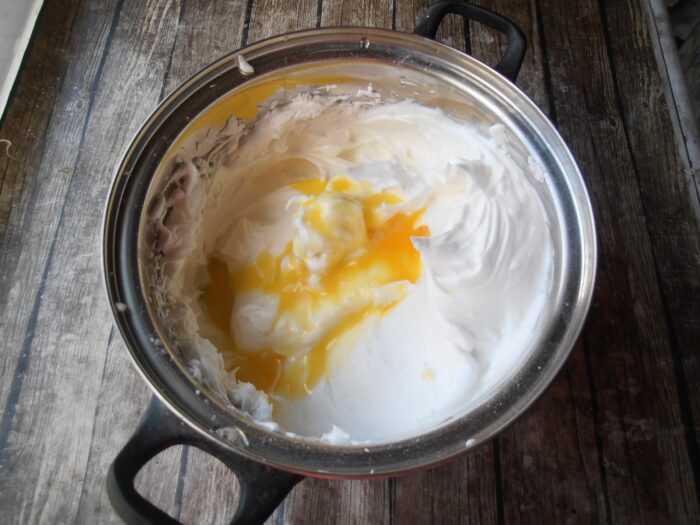 Add the egg yolks while beating