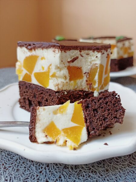 Side view of peach chocolate cake showing juicy peach pieces embedded in cream layer