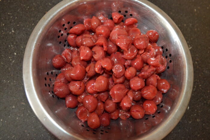 Положите вишни в дуршлаг