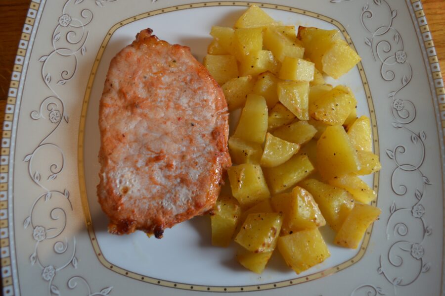 Close-up of pork chop with crisp potato cubes served on plate