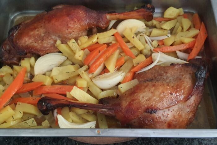 Arrange the duck legs and the vegetables together