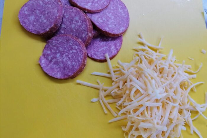 Corta el cervelat en rodajas o medias lunas